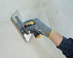 A plasterer skimming a plastered wall